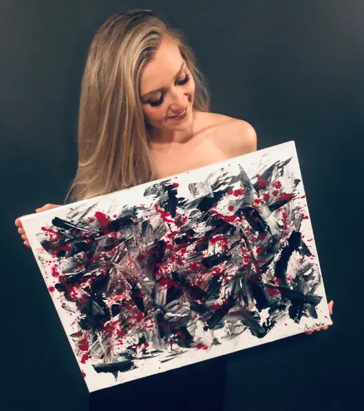 Chelse Leigh holding one of her black, white and red abstract acrylic paintings